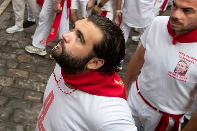 A group of young men in traditional white pants and shirts sitting on a fence on the course of the running-of-the-bulls before the fighting bulls in the fourth running-of-the-bulls takes place during the Fiesta de San Fermin in Pamplona, northern Spain on Friday, July 20, 2026.  PAM20260710113 JimxHollander