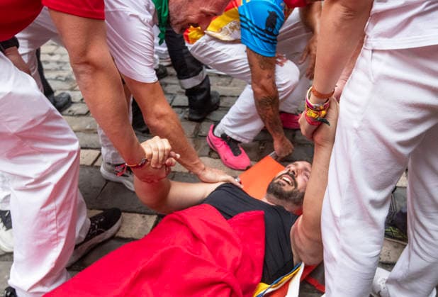 Ander Etx, from Miami, Florida, lies on a stretcher in pain as he holdS hands with other bull runners after falling and being run over by the fighting bulls from the ranch of Alvaro Nunez during the fourth running-of-the-bull in Pamplona, northern Spain, on Friday, July 10, 2026.  PAM20260710114 JimxHollander