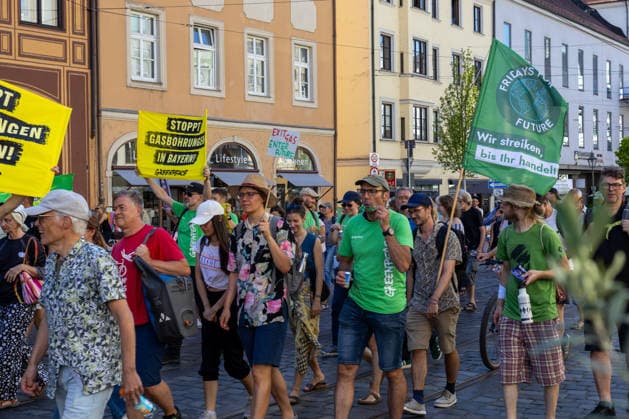 Augsburg, Bavaria, Germany - July 10, 2026: Demonstration by the climate justice movement Fridays for Future and GREENPEACE in Augsburg. Under the nationwide slogan: Protect the climate, fire the rich, the activists are protesting, among other things, against current gas infrastructure policy and planned gas drilling in Bavaria. Demonstrators march through the city carrying FFF flags and GREENPEACE signs: STOP GAS DRILLING IN BAVARIA! *** Demonstration der Klimaschutzbewegung Fridays for Future und GREENPEACE in Augsburg. Unter dem bundesweiten Motto: Klima schützen, Reiche entlassen, protestieren die Aktivisten unter anderem gegen die aktuelle Gas-Infrastrukturpolitik und geplante Gasbohrungen in Bayern. Demonstranten laufen durch