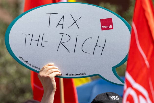 Demonstration für Solidarität statt Sozialabbau, Nürnberg, 11.07.2026 Eine Hand hält ein Schild mit der Aufschrift Tax the Rich in die Höhe. Das Schild trägt das Logo der Gewerkschaft ver.di und den Zusatz Gesundheit, Soziale und Wissenschaft . Im Hintergrund sind rote Demonstrationsfahnen zu sehen. Nürnberg Bayern Deutschland *** Demonstration for Solidarity Instead of Social Cuts, Nuremberg, July 11, 2026 A hand holds up a sign reading Tax the Rich. The sign bears the logo of the ver.di union and the words Health, Social Services, and Science. Red protest flags can be seen in the background. Nuremberg, Bavaria, Germany 20260711-1V9A5195-M4000