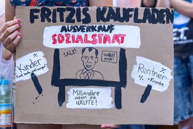 Demonstration für Solidarität statt Sozialabbau, Nürnberg, 11.07.2026 Demonstrantin hält ein selbst gestaltetes Protestschild mit der Aufschrift Fritzis Kaufladen - Ausverkauf Sozialstaat . Das Schild kritisiert satirisch den Abbau von Sozialleistungen und fordert höhere Abgaben für Milliardäre. Nürnberg Bayern Deutschland *** Demonstration for Solidarity Instead of Social Cuts, Nuremberg, July 11, 2026 A demonstrator holds a homemade protest sign reading Fritzi’s Store: Welfare State Clearance Sale. The sign satirically criticizes the cuts to social benefits and calls for higher taxes on billionaires. Nuremberg, Bavaria, Germany 20260711-286A1868-M4000