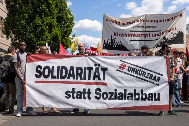 Demonstration für Solidarität statt Sozialabbau, Nürnberg, 11.07.2026 Demonstrierende tragen ein Banner mit der Aufschrift Solidarität statt Sozialabbau und dem Hashtag UNKÜRZBAR. Im Hintergrund ist ein weiteres Transparent mit der Aufschrift Klassenkampf und Streik sichtbar. Das Bündnis UNKÜRZBAR Mittelfranken protestiert gegen das Reformpaket der Bundesregierung. Nürnberg Bayern Deutschland *** Demonstration for Solidarity Instead of Social Cuts, Nuremberg, July 11, 2026 Demonstrators carry a banner reading Solidarity Instead of Welfare Cuts and the hashtag UNKÜRZBAR. In the background, another banner reading Class Struggle and Strike is visible. The UNKÜRZBAR Middle Franconia coalition is protesting against the refo 20260711-286A1882-M4000