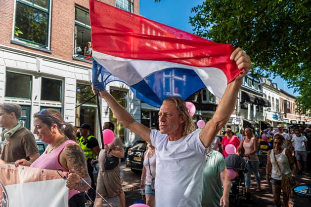 July 11, 2026, Schiedam, South Holland, Netherlands: 11 July 2026. An anti-asylum seeker center demonstrator displays a Dutch flag over his head. In Schiedam, the Netherlands, a pro-asylum seeker demonstration promoted by Extinction Rebellion countered a demonstration called the Vrouwenmars tegen het AZC (Women s March Against the AZC) promoted by anti-asylum seeker center groups. Both events took place in the center of Schiedam. Schiedam Netherlands - ZUMAp202 20260711_zip_p202_001 Copyright: xJamesxPetermeierx