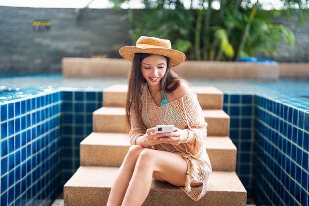 Junge hispanische Frau der Generation Z nutzt ihr Smartphone, um während des Sommerurlaubs am Pool des Resorts ihre sozialen Medien zu aktualisieren. Young Hispanic Gen Z Woman Using Smartphone to Update Social Media by Resort Pool During Summer Vacation (License=RF) ,model released, Symbolfoto Copyright: xZoonar.com SirijitxJongcharoenkulchaix 25270145 ,model released, Symbolfoto ,property released