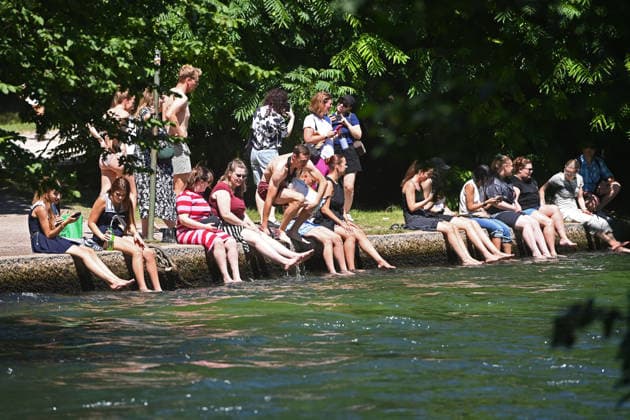 Wetterbild vom 12.07.2026 Menschen suchen Abkuehlung im Eisbach in Muenchen. Besters Sommerwetter bei Temperaturen um 30 Grad treibt die Menschen in Muenchen an die freie Luft und in den kuehlen Eisbach im Englischen Garten *** Weather photo from July 12, 2026: People seek relief from the heat in the Eisbach in Munich. Perfect summer weather, with temperatures around 30 degrees, is drawing people in Munich outdoors and into the cool Eisbach in the English Garden.