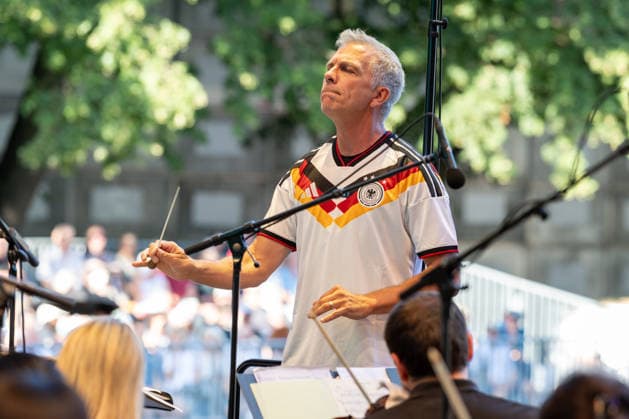 Klassik!Picknick mit dem Beethoven Orchester auf dem Kunst!Rasen Bonn Generalmusikdirektor Dirk KAFTAN im Deutschland Trikot - Das Beethoven Orchester Bonn unter der Leitung von Generalmusikdirektor Dirk KAFTAN beim Open-Air-Konzert KLASSIK!PICKNICK auf dem Kunst!Rasen Bonn-Gronau. Das Sommerprogramm steht unter dem Motto Fußball - passend zur WM 2026. Die Konzertreihe findet am Rande der Rheinaue am Bonner Rheinufer statt. Bonn Gronau Nordrhein-Westfalen Deutschland *** Classical Picnic with the Beethoven Orchestra on the Kunst Rasen in Bonn; General Music Director Dirk KAFTAN in the Germany jersey. The Beethoven Orchestra Bonn, conducted by General Music Director Dirk KAFTAN, at the open-air concert Classical Picnic on the Kunst Rasen Copyright: xMarcxJohnx