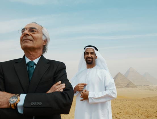 Selbstbewusste arabische Geschäftsleute zweier Generationen, die stolz vor den Pyramiden von Gizeh in Ägypten stehen ? einer im Anzug, der andere in traditioneller Kleidung aus den Vereinigten Arabischen Emiraten ? Idealbild Two confident Arab businessmen stand proudly before the Giza pyramids one in a dark suit one in traditional Emirati dress. Aspirational desert light ideal for Middle East business investment and (License=RF) ,model released, Symbolfoto Copyright: xZoonar.com benisxarapovicx 25291283 ,model released, Symbolfoto ,property released