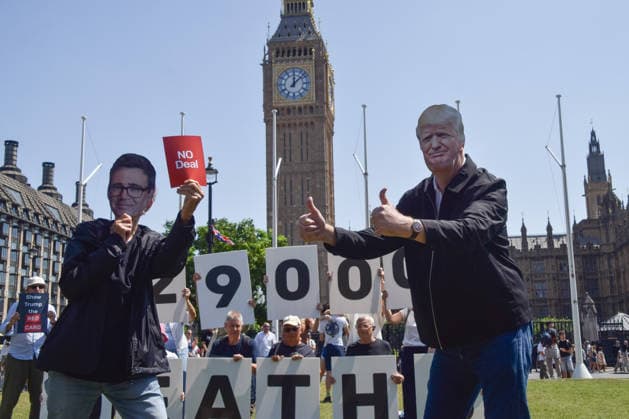 July 13, 2026, London, England, United Kingdom: An activist wearing an Andy Burnham mask shows a no deal red card to an activist wearing a Donald Trump mask during a protest in Parliament Square against the US-UK drug deal. An analysis has suggested that the trade deal could lead to 229,000 excess deaths in England as a result of diverting billions of pounds from essential NHS services to pay for new medicines. London United Kingdom - ZUMAv130 20260713_zip_v130_005 Copyright: xVukxValcicx