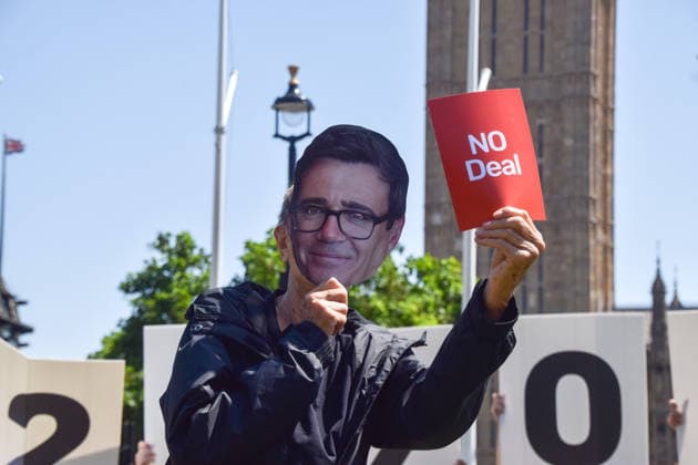 July 13, 2026, London, England, United Kingdom: An activist wearing an Andy Burnham mask holds up a no deal red card during a protest in Parliament Square against the US-UK drug deal. An analysis has suggested that the trade deal could lead to 229,000 excess deaths in England as a result of diverting billions of pounds from essential NHS services to pay for new medicines. London United Kingdom  - ZUMAv130 20260713_zip_v130_016 Copyright: xVukxValcicx