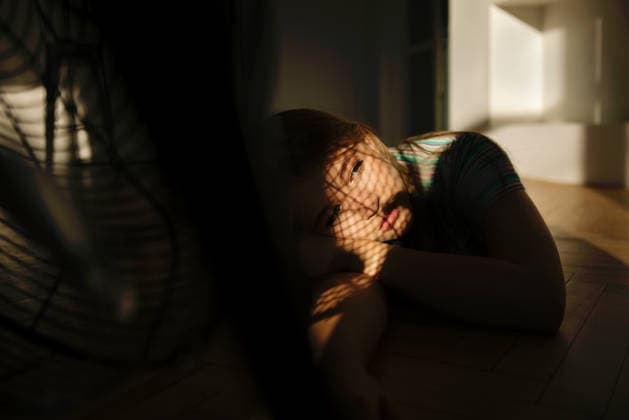 Ein junges Mädchen ruht sich auf dem Boden aus, den Kopf auf den Arm gestützt; Sonnenlicht wirft durch einen Ventilator Schatten in einem hellen Innenraum. Young girl lies on the floor with her head resting on her arm, sunlight filtering through a fan, creating interesting shadow patterns in the room (License=RF) ,model released, Symbolfoto Copyright: xZoonar.com DashaxPetrenkox 25305423 ,model released, Symbolfoto ,property released