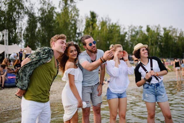 Group of young friends at summer festival. Group of cheerful young friends at summer festival, standing in lake water. model released