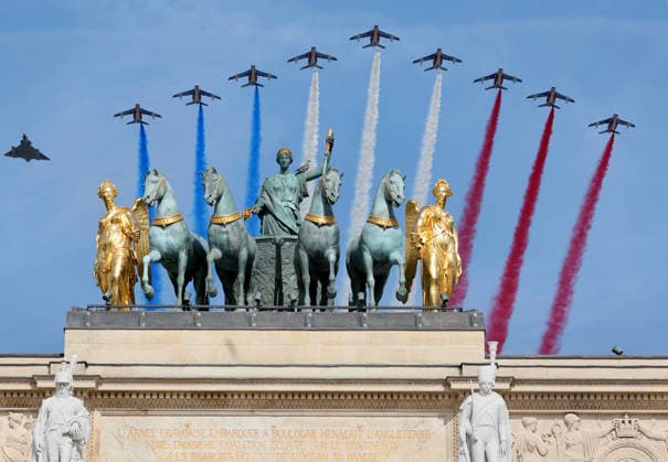 Jets from the French Air and Space Force s Patrouille de France trail blue, white, and red smokeÑthe colors of the French flagÑas they fly over the statues atop the entrance to the Tuileries Garden during the Bastille Day military parade in Paris, France, Tuesday, July 14, 2026.  PAR20260714103 MAYAxVIDON-WHITE