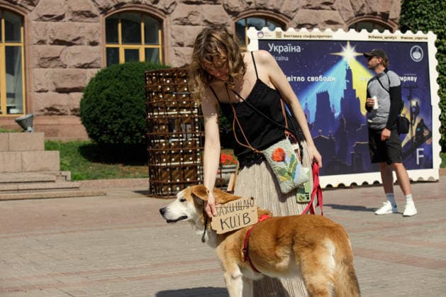 A woman stands by a dog wearing a placard reading I Defend Kyiv during the Preserve Affordable Transport in Kyiv rally against the increase in municipal transport fares outside the Kyiv City State Administration building, Kyiv, Ukraine, July 14, 2026. The capital plans to raise the fare for municipal transport to UAH 30 per single trip. The new tariffs will take effect from July 15, 2026. (Photo by Marianna Kotyk Ukrinform) Kyivans protest against municipal transport fare hike  Copyright: xMariannaxKotykx