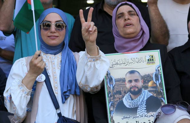 July 14, 2026, Nablus, Palestine: A Palestinian woman holds a portrait of her son while the other showing up a peace sign during a demonstration in downtown Nablus in the West Bank, demanding their release from Israeli prisons. Released prisoners said that prison guards fired rubber bullets at the Palestinian leader Marwan Barghouti inside his cell. Barghouti is serving five life sentences plus forty years, and has spent more than twenty-four years in Israeli prison. Nablus Palestine - ZUMAs197 20260714_aaa_s197_091 Copyright: xNasserxishatyehx