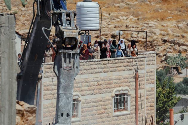 Hebron West Bank Home Demolition Palestinian residents watch as an excavator operates during a home demolition in Al-Deirat, south of Hebron, occupied West Bank on July 14, 2026. Israeli forces demolish the home of Osama Masaaf on the grounds that it lacked an Israeli-issued building permit, displacing a Palestinian family of eight. Hebron West Bank Palestinian Territories Copyright: xMosabxShawerx