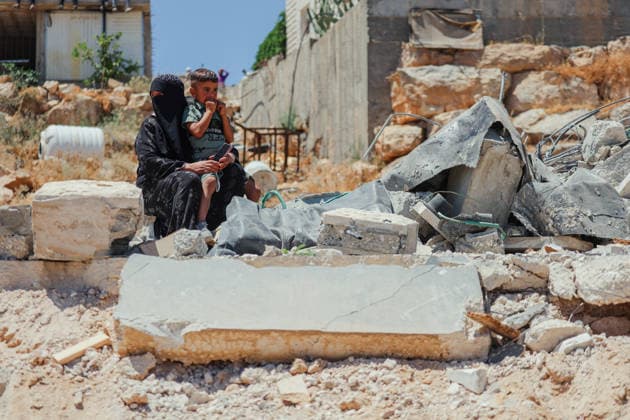 Hebron West Bank Home Demolition A Palestinian woman sits with a child among the rubble of the demolished home of Osama Masaaf s family in Al-Deirat, south of Hebron, occupied West Bank on July 14, 2026. Israeli forces demolish the home of Osama Masaaf on the grounds that it lacked an Israeli-issued building permit, displacing a Palestinian family of eight. Hebron West Bank Palestinian Territories Copyright: xMosabxShawerx