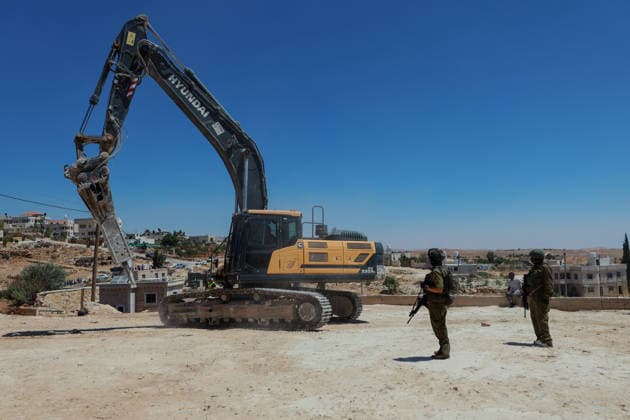 Hebron West Bank Home Demolition Israeli forces stand near an excavator as a Palestinian home is demolished in Al-Deirat, south of Hebron, occupied West Bank on July 14, 2026. Israeli forces demolish the home of Osama Masaaf on the grounds that it lacked an Israeli-issued building permit, displacing a Palestinian family of eight. Hebron West Bank Palestinian Territories Copyright: xMosabxShawerx