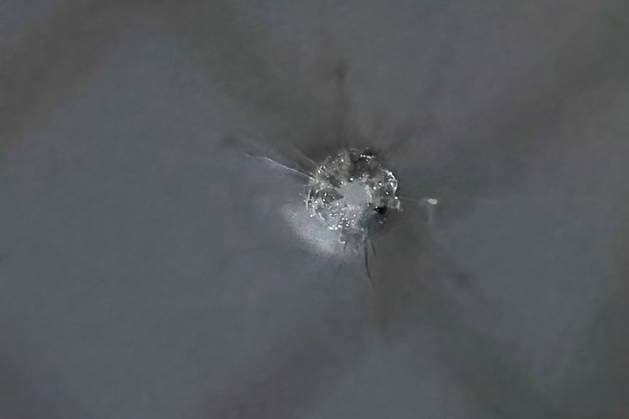 Das Einschussloch zeigt den charakteristischen Geschosstritt in einer Glasscheibe. Die Aufnahme ist Beweismaterial für die ballistischen Ermittlungen der Kriminalpolizei. Nach Zeugenaussagen hat der verdächtige Mann am Dienstagabend gegen 20:20 Uhr in der Unterdürrbacher Straße Würzburg mehrfach mit einer Handfeuerwaffe geschossen. Würzburg Unterdürrbach, Bayern, 14. Juli 2026 *** The bullet hole shows the characteristic impact mark left by a bullet in a pane of glass. The photograph serves as evidence for the criminal investigation department’s ballistic analysis. According to witness statements, the suspect fired a handgun multiple times on Tuesday evening around 8:20 p.m. on Unterdürrbacher Straße in Würzburg Würzburg Unterdürrbach, Bava Copyright: HMBxMedia xHeikoxBecker
