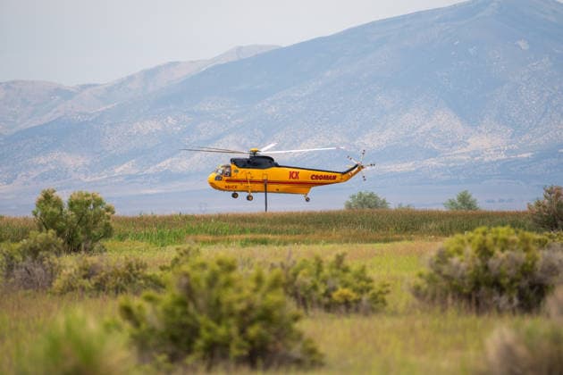 July 14, 2026, Vernon, Utah, USA: A firefighting helicopter flies low over vegetation with its snorkel hose hanging down near Vernon, Utah, on Tuesday, July 14, 2026. Helicopters are utilizing local water sources like Atherley Reservoir to support ground operations on the active Stookey wildfire in Tooele County. Vernon USA - ZUMAm292 20260714_znp_m292_017 Copyright: xCharlesxMcClintockxWilsonx