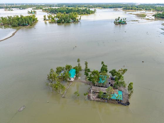 Aftermath Of Floodwaters In Chattogram An aerial drone perspective highlights a single, vulnerable homestead trapped within an expansive body of floodwater in Banshkhali, Chattogram, Bangladesh, on July 14, 2026. Although the flood waters in Banshkhali and Satkania in Chittagong are slowly receding.Many areas are still knee-deep in water, and as the water recedes, collapsed mud houses, damaged structures, destroyed brick kilns and severely damaged agricultural land are becoming visible, displacing thousands of people and leaving them struggling to meet their basic needs. Chattogram Bangladesh  Copyright: xZakirxHossainx originalFilename: hossain-notitle260714_npCPF.jpg