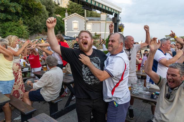 Public Viewing England - Argentinien in Torquay Torquay, England- 15.7.2026: Fußballfans aus Torquay feiern bei einem Public Viewing in einem Pub am Hafen von Torquay das 1:0 für England durch Anthony Gordon während des Fussballspiels England gegen Argentinien bei der WM 2026. England steht im Halbfinale der Weltmeisterschaft 2026 gegen Argentinien und kann zum zweiten Mal in seiner Geschichte nach 1966 Weltmeister im Männerfußball werden England