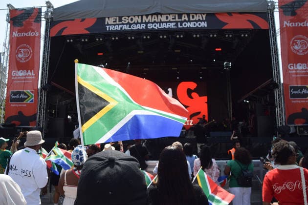 July 18, 2026, London, England, United Kingdom: A member of the audience waves a South African flag at the Nelson Mandela Day celebration in Trafalgar Square, honouring the life and legacy of Nelson Mandela. This year also marks the 30th anniversary of the South African Constitution. London United Kingdom - ZUMAv130 20260718_zip_v130_046 Copyright: xVukxValcicx