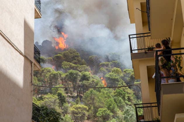 Wildfire Spreads Amid Heatwave in Sicily A woman holding a child looks at flames from a wildfire on a hill from the balcony of an apartment building in Modica, Sicily, Italy, on July 18, 2026. Wildfires were reported in parts of Sicily as high temperatures persisted across the region. Modica Sicily Italy Copyright: xElvisxTakahashixMantellox