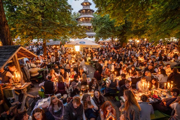 Tausende Besucher bei Kocherlball am Chinesischen Turm, Biertrinken bei Kerzenschein, hier um kurz nach 5 Uhr früh, München, 19. Juli 2026 Deutschland, München, 19. Juli 2026, Biertrinken bei Kerzenschein, traditioneller Kocherlball am Chinesischen Turm, Englischer Garten, Tausende Besucher um kurz nach 5 Uhr früh, der Biergarten ist voll, manche Besucher sind schon um 3 Uhr früh im Biergarten, um noch einen Platz zu ergattern, die Menschen trinken ein Bier, essen eine Brotzeit, tragen Tracht, Tradition entstand im 19. Jahrhundert, als Hauspersonal, Dienstboten und KöchInnen in den frühen Morgenstunden vor Dienstbeginn gefeiert und getanzt haben, Tradition wurde ab 1989 wiederbelebt, traditionell am 3. Sonntag im Juli, feiern, Tradit