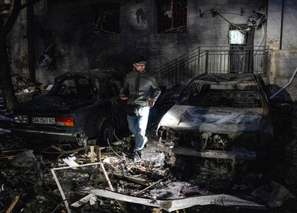 A man lights his way as he walks between two destroyed cars in the Solomianskyi district after a Russian attack on Kyiv, Ukraine, July 19, 2026. The Russian army launched a massive strike on the Ukrainian capital with ballistic missiles. According to preliminary data from the State Emergency Service of Ukraine, one person was killed and 15 were injured. Falling debris and fires were reported in five districts of the city, while an underpass near the Lukianivska metro station sustained a direct hit. (Photo by Danylo Antoniuk Ukrinform) Russian army attacks Kyiv with ballistic missiles  Copyright: xDanyloxAntoniukx