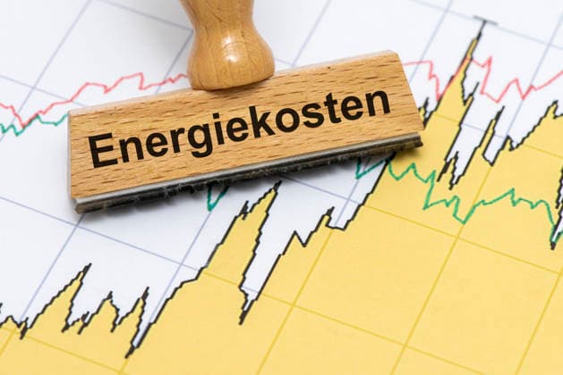 Energiekosten und Energiepreise Ein Holzstempel ist beschriftet mit dem Aufdruck Energiekosten als Symbolbild für steigende Kosten für Energie in Wirtschaft, Industrie und Handel - FOTOMONTAGE - NUR FÜR REDAKTIONELLE VERWENDUNG - *** Energy Costs and Energy Prices: A wooden stamp bears the inscription Energy Costs as a symbolic image representing rising energy costs in business, industry, and commerce. PHOTOMONTAGE FOR EDITORIAL USE ONLY