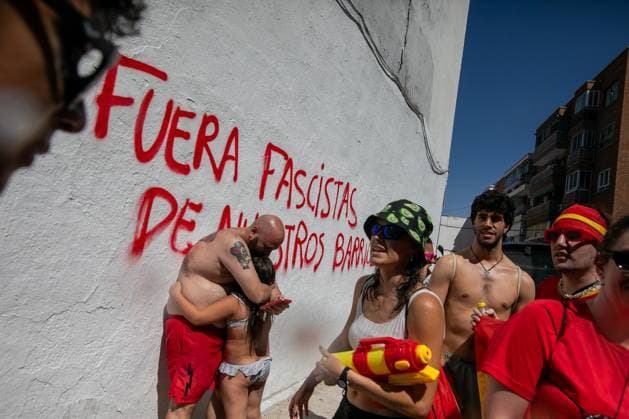 July 19, 2026, Madrid, Madrid, Spain: A man hugs a girl in front of a wall with graffiti that says fascists out of our neighborhood .during the Water Battle in the working-class neighborhood of Vallecas, Madrid. This celebration began in 1981 due to the high temperatures, when residents started throwing water at each other. It is also part of the festivities for the Virgen del Carmen, patron saint of sailors. Madrid Spain - ZUMAs197 20260719_aaa_s197_133 Copyright: xDavidxCanalesx