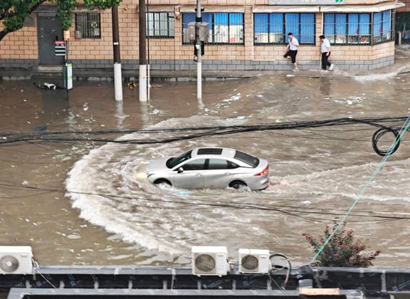 SHANGHAI, CHINA - JULY 19: A car drives through flooded street due to heavy rainstorms on July 19, 2026 in Shanghai, China. Heavy rain caused severe waterlogging in roads and residential areas in Shanghai s Yangpu District. Shanghai Meteorological Observatory upgraded the rainstorm alert from yellow to orange for the central urban area at 14:35 on July 19.  Copyright: xVCGx 111655264427