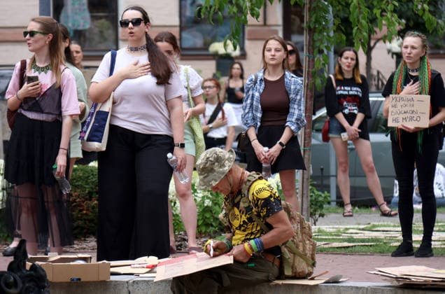 A man writes on a piece of cardboard with a marker as demonstrators perform the national anthem with placards during a protest action against the dismissal of Ukrainian Defence Minister Mykhailo Fedorov in Ivana Franka Square outside the Ivan Franko National Academic Drama Theatre and near the Office of the President, Kyiv, Ukraine, July 19, 2026. (Photo by Pavlo Bahmut Ukrinform) Day Four of protest action against dismissal of Mykhailo Fedorov in Kyiv  Copyright: xPavloxBahmutx