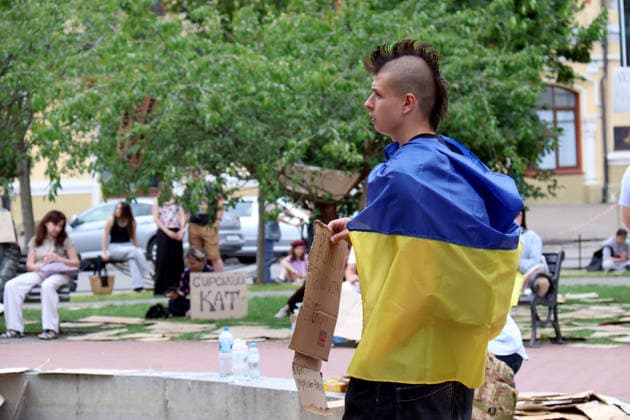 A man with a mohawk wrapped in a national flag holds a placard during a protest action against the dismissal of Ukrainian Defence Minister Mykhailo Fedorov in Ivana Franka Square outside the Ivan Franko National Academic Drama Theatre and near the Office of the President, Kyiv, Ukraine, July 19, 2026. (Photo by Pavlo Bahmut Ukrinform) Day Four of protest action against dismissal of Mykhailo Fedorov in Kyiv  Copyright: xPavloxBahmutx