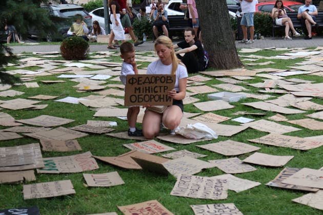A boy and a woman holding a placard with the slogan Fedorov Is Defence Minister stay on the lawn covered with placards walk past the monument to Ukrainian theatre director, film and theatre actor Hnat Yura during a protest action against the dismissal of Ukrainian Defence Minister Mykhailo Fedorov in Ivana Franka Square outside the Ivan Franko National Academic Drama Theatre and near the Office of the President, Kyiv, Ukraine, July 19, 2026. (Photo by Pavlo Bahmut Ukrinform) Day Four of protest action against dismissal of Mykhailo Fedorov in Kyiv  Copyright: xPavloxBahmutx