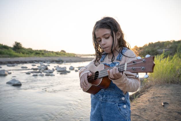Young girl playing ukulele by a river at sunset Reque, Lambayeque, Peru CR_BILL260717-2080718-01 ,model released, Symbolfoto ,property released