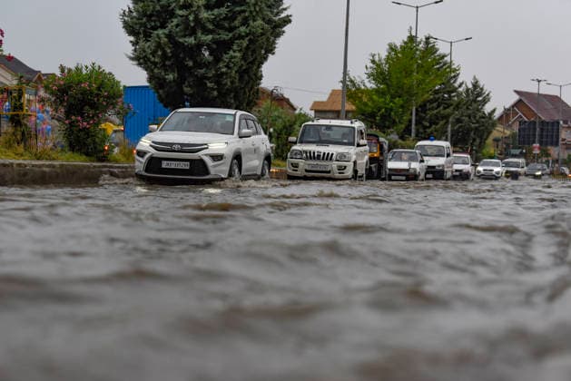 July 20, 2026, Srinagar, Jammu And Kashmir, India: People travel with their vehicles through a waterlogged road during heavy rainfall in Srinagar.Torrential rain unleashed flash floods and landslides in Pir Panjal region of J&Ks Poonch and Rajouri districts Sunday, killing at least 14 people, leaving several missing and burying homes under walls of water, rock and mud that barrelled down mountain slopes. Officials said the toll could rise as rescuers searched for those trapped beneath debris. Srinagar India  - ZUMAz120 20260720_zip_z120_003 Copyright: xBasitxZargarx