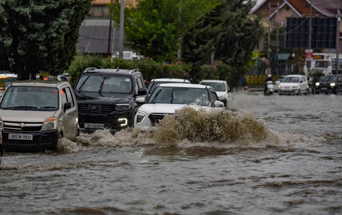 July 20, 2026, Srinagar, Jammu And Kashmir, India: People travel with their vehicles through a waterlogged road during heavy rainfall in Srinagar.Torrential rain unleashed flash floods and landslides in Pir Panjal region of J&Ks Poonch and Rajouri districts Sunday, killing at least 14 people, leaving several missing and burying homes under walls of water, rock and mud that barrelled down mountain slopes. Officials said the toll could rise as rescuers searched for those trapped beneath debris. Srinagar India  - ZUMAz120 20260720_zip_z120_008 Copyright: xBasitxZargarx