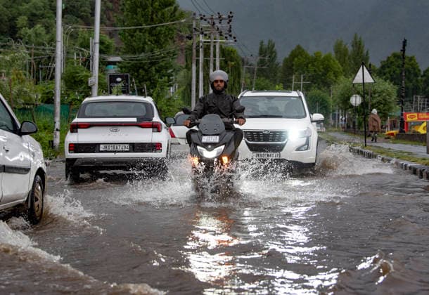 July 20, 2026, Srinagar, Jammu And Kashmir, India: People travel with their vehicles through a waterlogged road during heavy rainfall in Srinagar.Torrential rain unleashed flash floods and landslides in Pir Panjal region of J&Ks Poonch and Rajouri districts Sunday, killing at least 14 people, leaving several missing and burying homes under walls of water, rock and mud that barrelled down mountain slopes. Officials said the toll could rise as rescuers searched for those trapped beneath debris. Srinagar India  - ZUMAz120 20260720_zip_z120_016 Copyright: xBasitxZargarx