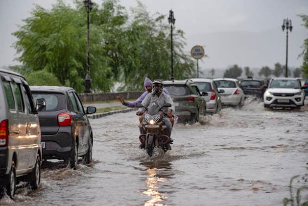 July 20, 2026, Srinagar, Jammu And Kashmir, India: People travel with their vehicles through a waterlogged road during heavy rainfall in Srinagar.Torrential rain unleashed flash floods and landslides in Pir Panjal region of J&Ks Poonch and Rajouri districts Sunday, killing at least 14 people, leaving several missing and burying homes under walls of water, rock and mud that barrelled down mountain slopes. Officials said the toll could rise as rescuers searched for those trapped beneath debris. Srinagar India - ZUMAz120 20260720_zip_z120_018 Copyright: xBasitxZargarx