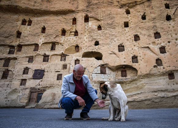 Historic grain granaries stand the test of time in Turkiye s Karaman TASKALE, KARAMAN - JULY 20: A resident pets a dog in front of the historic rock-carved grain granaries in Taskale village of Karaman, Turkiye, on July 20, 2026. Carved by hand into a single rock mass, the centuries-old granaries continue to preserve Anatolia s agricultural heritage with their distinctive architecture. More than 250 granaries remain in active use by local residents, naturally preserving grain thanks to the humidity and temperature balance provided by the clay-rich limestone. Mahmut Serdar Alakus Anadolu Karaman Turkey. Editorial use only. Please get in touch for any other usage.  Copyright: x2026xAnadoluxMahmutxSerdarxAlakuÅüx