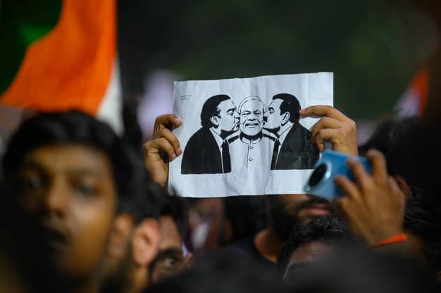 July 20, 2026, New Delhi, New Delhi, India: A protester holds up a placard depicting billionaires Mukesh Ambani and Gautam Adani kissing the cheeks of Prime Minister Narendra Modi, symbolizing protesters allegations of a corruption nexus between the two industrialists and the Modi government, at Jantar Mantar during demonstrations by the Cockroach Janata Party (CJP) demanding the resignation of Education Minister Dharmendra Pradhan over alleged irregularities in the NEET-UG exam, July 20, 2026. New Delhi India - ZUMAm184 20260720_zip_m184_010 Copyright: xAnkitxRoyxMajumderx