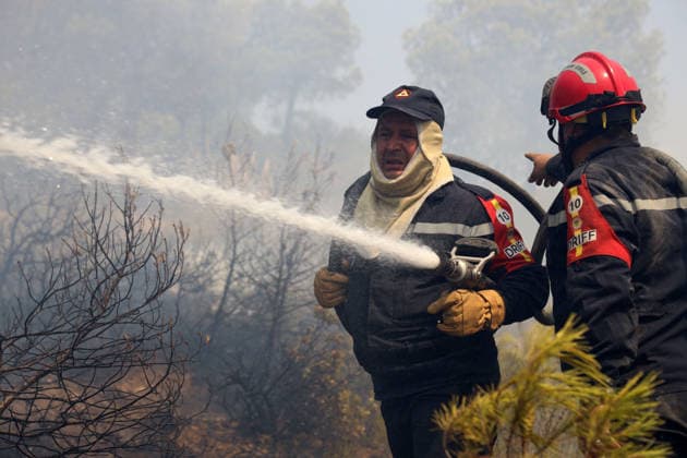 (260721) -- ALGIERS, July 21, 2026 -- Firefighters work against a wildfire on a mountain in El Hachimia, northern Algeria, on July 21, 2026. Six people have been killed in wildfires sweeping across northern Algeria as a prolonged heat wave continues to fuel forest and vegetation fires in several provinces, the Algerian Ministry of the Interior, Local Authorities and Transports said Tuesday. (Photo by Xinhua) ALGERIA-EL HACHIMIA-WILDFIRES BillelxBensalem 