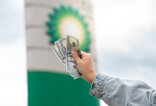 US Money And Financial Services. A woman holds United States dollar banknotes in front of a BP fuel price display at a petrol station in Krakow, Poland, on July 21, 2026. High fuel prices continue to affect household budgets, transportation costs, and consumer spending. Krakow Poland  Copyright: xMarcinxGolbax originalFilename: golba-usmoneya260721_np42k.jpg