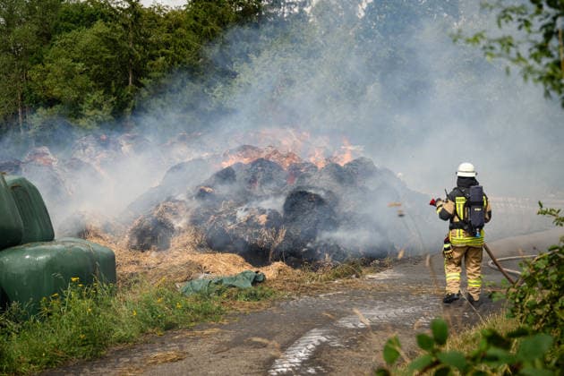 Polizeihubschrauber sucht nach Brandstiftern 200 Rundballen in Flammen 70 Einsatzkräfte im Einsatz Am 22.07.2026 brannten in Tiefenbach im Hunsrück gegen 13:00 Uhr rund 200 Rundballen an drei nahegelegenen Einsatzstellen. Zwei Brandstellen lagen im Wald, eine auf einem Sportplatz. Ein Polizeihubschrauber suchte das Gebiet nach möglichen Tätern ab, während die Polizei Fahrzeuge auf der Straße kontrollierte. Rund 70 Einsatzkräfte errichteten eine Riegelstellung zu angrenzenden Silageballen und dem Wald und ließen das Feuer kontrolliert abbrennen. Tiefenbach (Hunsrück) Rheinland-Pfalz Deutschland *** Police helicopter searches for arsonists; 200 round bales in flames; 70 emergency responders on the scene. On July 22, 2026, at