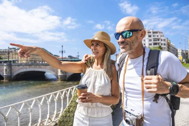 Seniorenpaar genießt den Sommerurlaub, spaziert entlang einer Flusspromenade, macht Besichtigungstouren und zeigt auf ein Wahrzeichen, erlebt gemeinsam Tourismus und Freizeitaktivitäten in einer sonnigen urbanen Umgebung Senior couple enjoying summer vacation, walking along a river promenade, sightseeing and pointing to a landmark, experiencing tourism and leisure activities together in a sunny urban setting Copyright: imageBROKER UnaixHuizi ibxuhu18491584.jpg ,model released, Symbolfoto ,property released