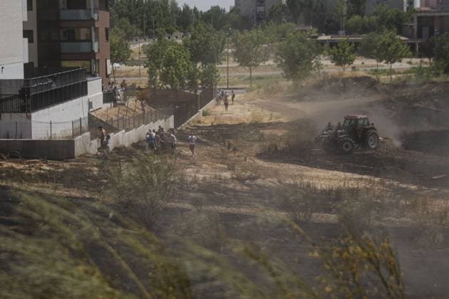July 24, 2026, Navalcarnero, Spain: NAVALCARNERO, SPAIN Ã¢â‚¬ JULY 24, 2026: Municipal workers and local residents carry out cooling operations while tractors create firebreaks after a vegetation fire broke out near residential areas in Navalcarnero, Madrid. Emergency services worked to secure the affected area and prevent the flames from spreading further amid high temperatures and dry conditions. Navalcarnero Spain  - ZUMAq101 20260724_zna_q101_091 Copyright: xEugenioxRodriguezxRigox