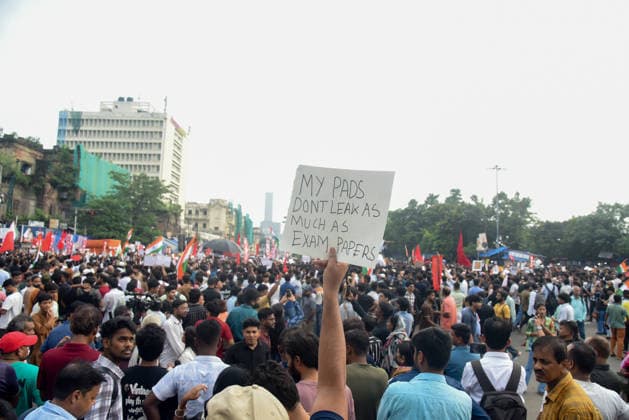 Kolkata Students Protest Pradhan A demonstrator holds a placard reading My pads don™t leak as much as exam papers above the crowd in Kolkata, India, on July 24, 2026. The rally, titled All Cockroaches of Bengal, marched from Sealdah to Dharmatala to protest against Union Education Minister Dharmendra Pradhan and alleged police violence in Delhi, with students from several organizations taking part. Kolkata West Bengal India Copyright: xAmitxGhoshx