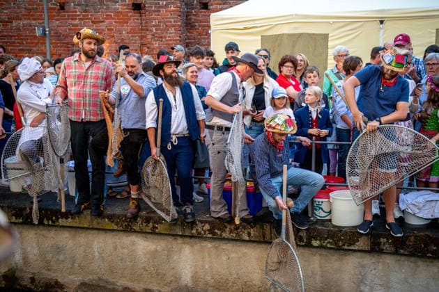 Ein Blick auf das traditionelle Bachausfischen während des Fischertags in Memmingen. Zahlreiche Fischer in teils historischer Kleidung waten durch den Stadtbach, um Fische zu fangen. Dicht gedrängt stehen Zuschauer am Ufer und verfolgen das Spektakel, das jährlich tausende Besucher anzieht. Im Hintergrund sind die historischen Mauern der Stadt zu sehen. Der Memminger Fischertag ist eines der ältesten und bekanntesten Volksfeste in Bayern. Memmingen Bayern Deutschland *** A look at the traditional stream fishing during Fishermen’s Day in Memmingen. Numerous fishermen, some in historical attire, wade through the town stream to catch fish. Spectators stand crowded together on the bank, watching the spectacle, which attracts thousands of
