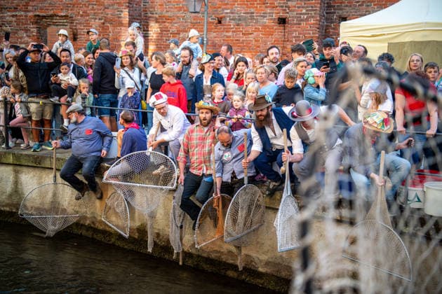 Ein Blick auf das traditionelle Bachausfischen während des Fischertags in Memmingen. Zahlreiche Fischer in teils historischer Kleidung waten durch den Stadtbach, um Fische zu fangen. Dicht gedrängt stehen Zuschauer am Ufer und verfolgen das Spektakel, das jährlich tausende Besucher anzieht. Im Hintergrund sind die historischen Mauern der Stadt zu sehen. Der Memminger Fischertag ist eines der ältesten und bekanntesten Volksfeste in Bayern. Memmingen Bayern Deutschland *** A look at the traditional stream fishing during Fishermen’s Day in Memmingen. Numerous fishermen, some in historical attire, wade through the town stream to catch fish. Spectators stand crowded together on the bank, watching the spectacle, which attracts thousands of